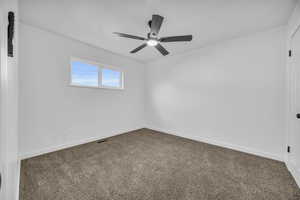 Carpeted empty room featuring ceiling fan