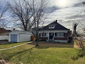 View of front facade with an outbuilding, a garage, and a front yard