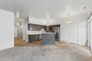 Kitchen featuring a center island, light neutral carpet, pendant lighting, and appliances with stainless steel finishes