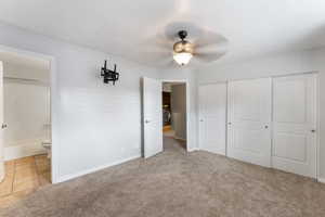 Unfurnished bedroom featuring ensuite bathroom, ceiling fan, light colored carpet, washer / clothes dryer, and a closet