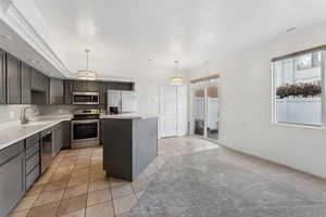 Kitchen with pendant lighting, a center island, a healthy amount of sunlight, and appliances with stainless steel finishes