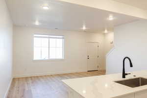 Kitchen with light stone counters, light hardwood / wood-style flooring, and sink