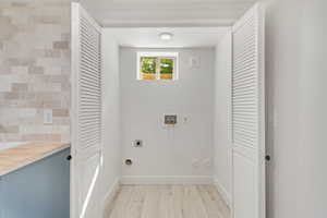 Laundry area with hookup for a washing machine, light wood-type flooring, and electric dryer hookup