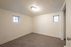 Basement featuring a textured ceiling, dark carpet, and a wealth of natural light