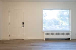 Foyer entrance with radiator, a wealth of natural light, and light hardwood / wood-style floors