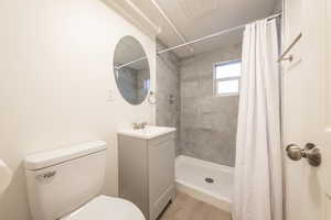 Bathroom featuring vanity, toilet, a shower with shower curtain, and hardwood / wood-style flooring