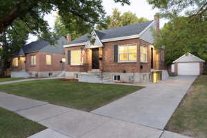 View of front facade featuring a garage, an outbuilding, and a front yard