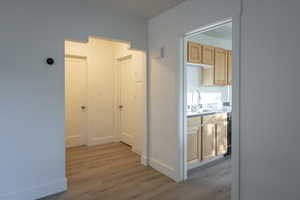 Corridor featuring light wood-type flooring and sink