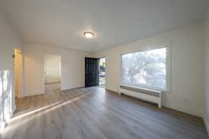 Spare room with radiator heating unit and light hardwood / wood-style floors