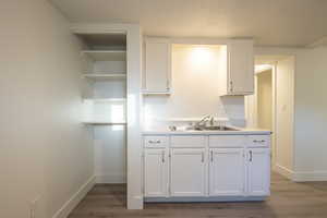 Kitchen with white cabinets, light hardwood / wood-style floors, and sink