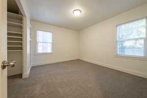 Unfurnished room featuring dark carpet and a healthy amount of sunlight