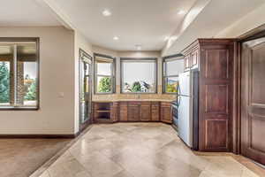 Kitchen featuring stainless steel fridge, backsplash, light colored carpet, and a healthy amount of sunlight