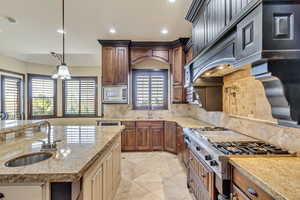 Kitchen with stainless steel appliances, light stone counters, tasteful backsplash, and sink