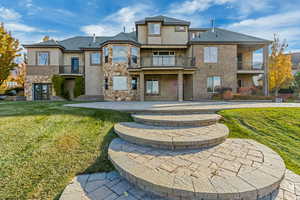 Back of property featuring a lawn, a patio area, and a balcony