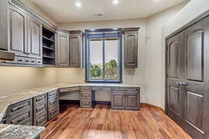 Unfurnished office featuring dark wood-type flooring and built in desk