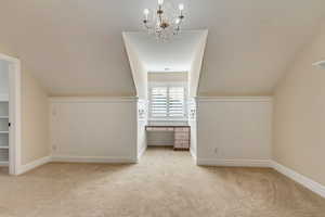 Bonus room featuring light colored carpet, an inviting chandelier, and lofted ceiling