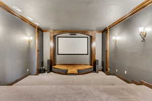 Carpeted home theater featuring ornamental molding