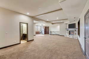 Unfurnished living room with a stone fireplace and light colored carpet