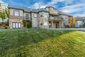 View of front of property with french doors, a balcony, and a front lawn