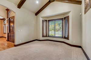 Unfurnished room with hardwood / wood-style floors and lofted ceiling with beams