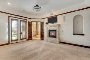 Unfurnished living room with a chandelier, carpet floors, a fireplace, and ornamental molding