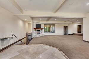 Carpeted living room featuring a fireplace and beam ceiling