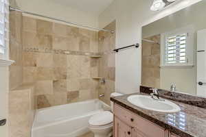 Full bathroom with vanity, tiled shower / bath combo, and toilet