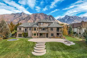 Rear view of house featuring a yard, a fire pit, a mountain view, a balcony, and a patio area