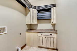 Clothes washing area featuring cabinets, hookup for a washing machine, light tile patterned floors, and electric dryer hookup