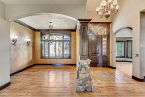 Entryway with ornamental molding, light hardwood / wood-style floors, a textured ceiling, and a notable chandelier