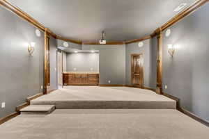 Carpeted home theater with ornamental molding