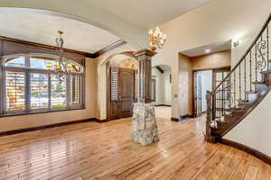 Entryway featuring light wood-type flooring, ornamental molding, and an inviting chandelier