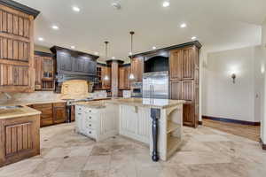 Kitchen featuring a center island, sink, appliances with stainless steel finishes, tasteful backsplash, and light stone counters