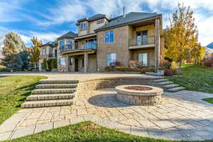 Exterior space with a lawn, a patio area, a balcony, and a fire pit