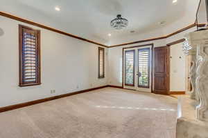 Spare room with a notable chandelier, light colored carpet, and ornamental molding