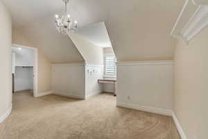 Additional living space featuring a chandelier, light colored carpet, and lofted ceiling