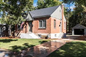 View of front of house featuring a garage, an outbuilding, and a front yard