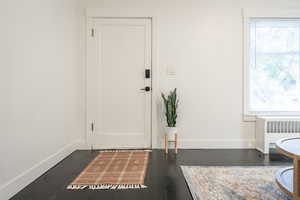 Doorway with radiator heating unit and dark wood-type flooring