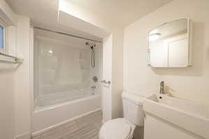 Bathroom featuring hardwood / wood-style flooring, toilet, and tub / shower combination