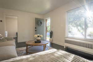 Living room with radiator heating unit and dark wood-type flooring