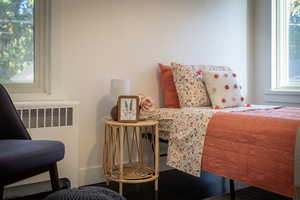 Bedroom featuring multiple windows and radiator heating unit