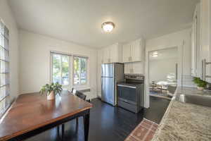 Kitchen featuring radiator, white cabinetry, stainless steel appliances, light stone counters, and dark hardwood / wood-style flooring