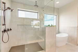 Bathroom featuring shower with separate bathtub and tile walls