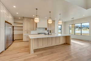 Kitchen featuring an island with sink, pendant lighting, and appliances with stainless steel finishes