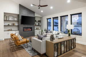 Living room featuring a tile fireplace, ceiling fan, vaulted ceiling, and hardwood / wood-style flooring