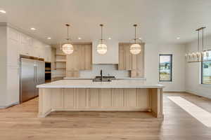 Kitchen with a large island, decorative light fixtures, and appliances with stainless steel finishes