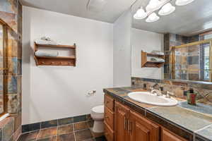 Bathroom with a shower with door, vanity, decorative backsplash, and toilet