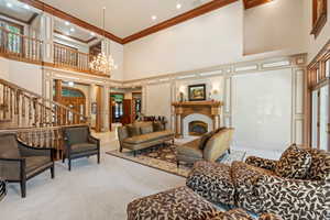 Living room featuring ornamental molding, a high ceiling, a chandelier, and plenty of natural light