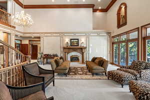 Living room with a towering ceiling, a notable chandelier, carpet floors, and crown molding