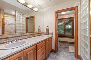 Bathroom featuring toilet, vanity, tile patterned floors, and a shower with door